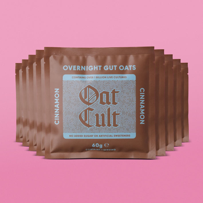 Multiple packages of Oat Cult Overnight Gut Oats cinnamon on a pink background